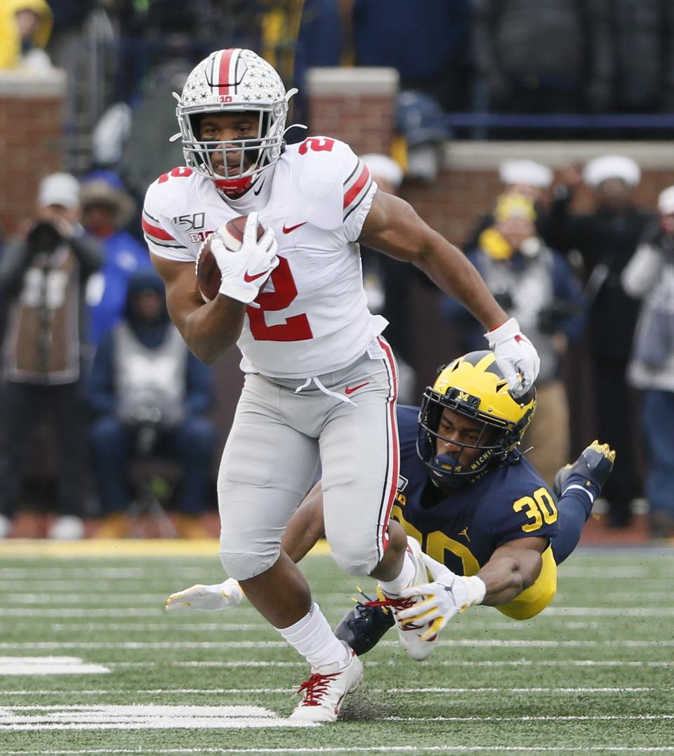 Ohio State running back J.K. Dobbins breaks a tackle attempt by Michigan defensive back Daxton Hill in 2019.