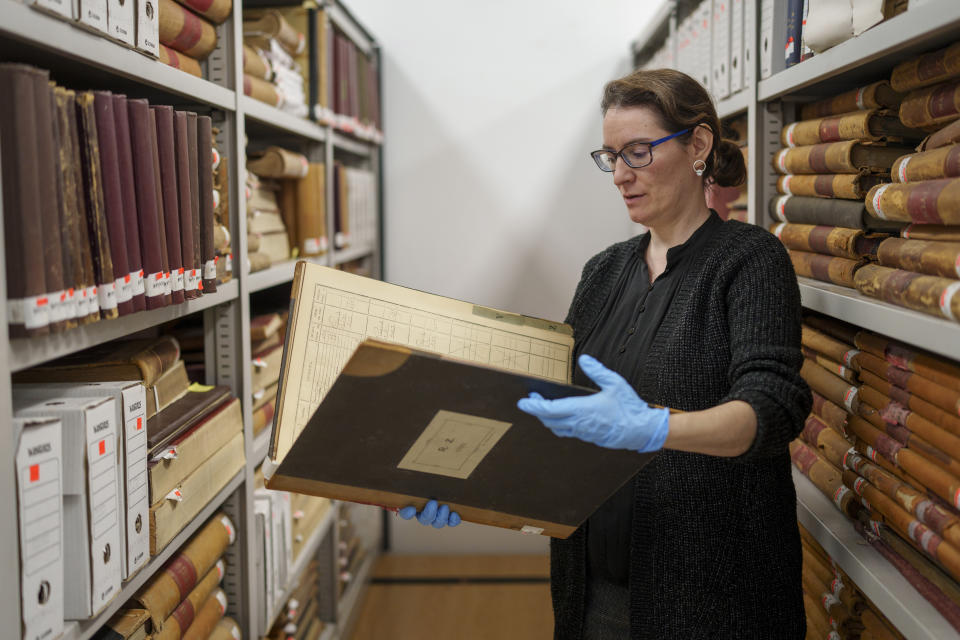 Archive and library manager Cristina de Mora shows a part of the archive collection at the Royal Tapestry Factory in Madrid, Spain, Friday, Nov. 30, 2023. Since its foundation in 1721, the Royal Tapestry Factory of Madrid has not stopped producing. It was Philip V, then King of Spain, who had the factory built with the help of Catholic craftsmen from Flanders to replace the lack of private initiative that existed at the time. (AP Photo/Manu Fernandez)