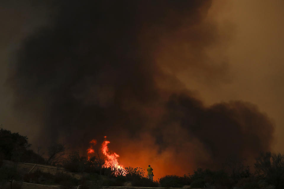 FILE - In this Aug. 8, 2018, file photo, a photographer takes pictures of a wildfire burning near a residential area in Lake Elsinore, Calif. Photographers have captured searing, intimate images of active and dangerous wildfires burning California, due in large part to a state law that guarantees press virtually unfettered access to disaster sites. That’s not the case everywhere as rules about media access vary by state, and even by government agency. (AP Photo/Jae C. Hong, File)