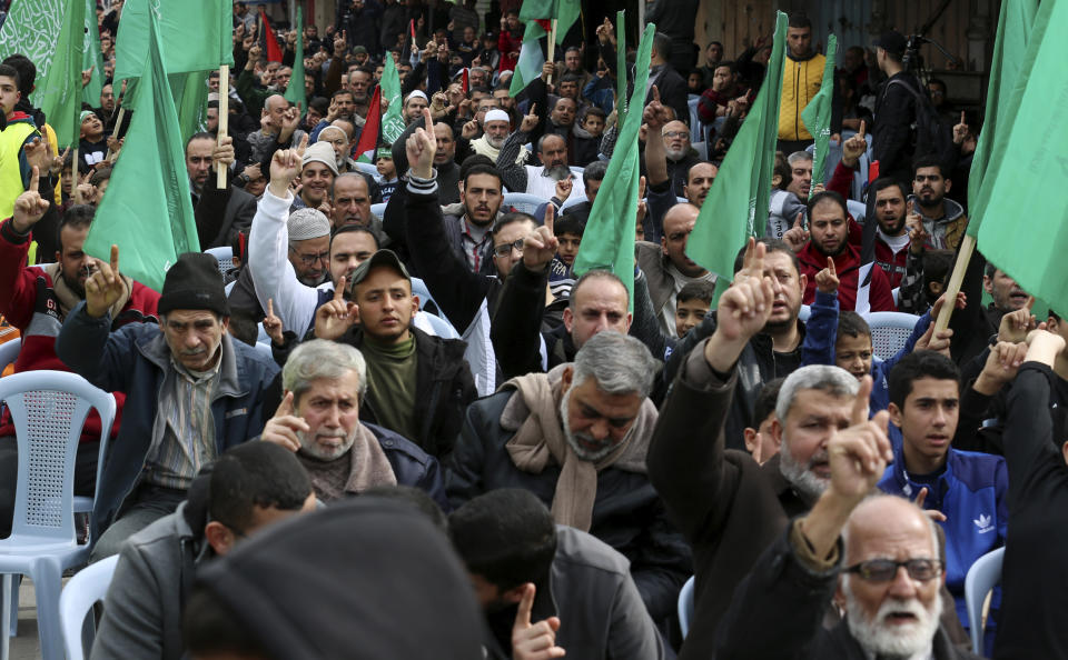 Hamas supporters raise their fingers up while chant slogans as others wave their green flags during a protest against the Mideast plan announced by U.S. President Donald Trump, after the Friday prayer at the main road in Gaza City, Friday, Feb. 14, 2020. (AP Photo/Adel Hana)