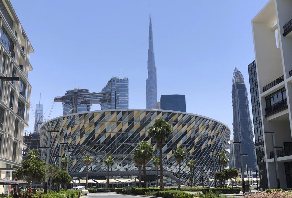 This Tuesday, April 16, 2019 photo shows the Coca Cola Arena in front of world tallest building, Burj Khalifa, in Dubai, United Arab Emirates. Dubai unveils its latest mega-project, a stadium and arena in the heart of a super luxe shopping and dining destination, even as the economy slows down and thousands of jobs are being axed across the emirate. (AP Photo/Kamran Jebreili)