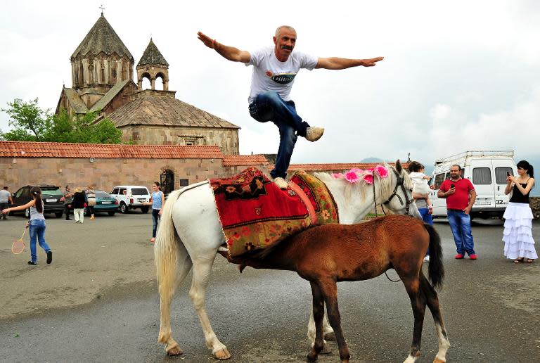 A man dances on a horse in front of 13th century's St.John Cathedral in the Armenian-controlled Azerbaijani region of Nagorny Karabakh on June 27, 2013