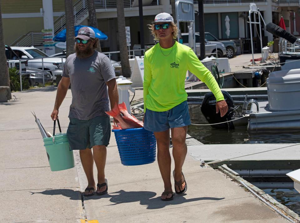 Charter boat crew Tyler Massey and Riley Riggs unload the day's Red Snapper catch after a successful fishing trip on Thursday, June 16, 2022.