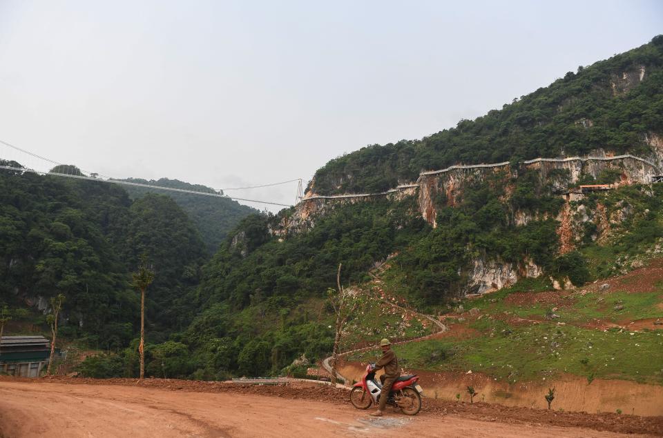 A man rides his motorbike under the Bach Long glass bridge in Moc Chau district in Vietnam's Son La province on April 29, 2022