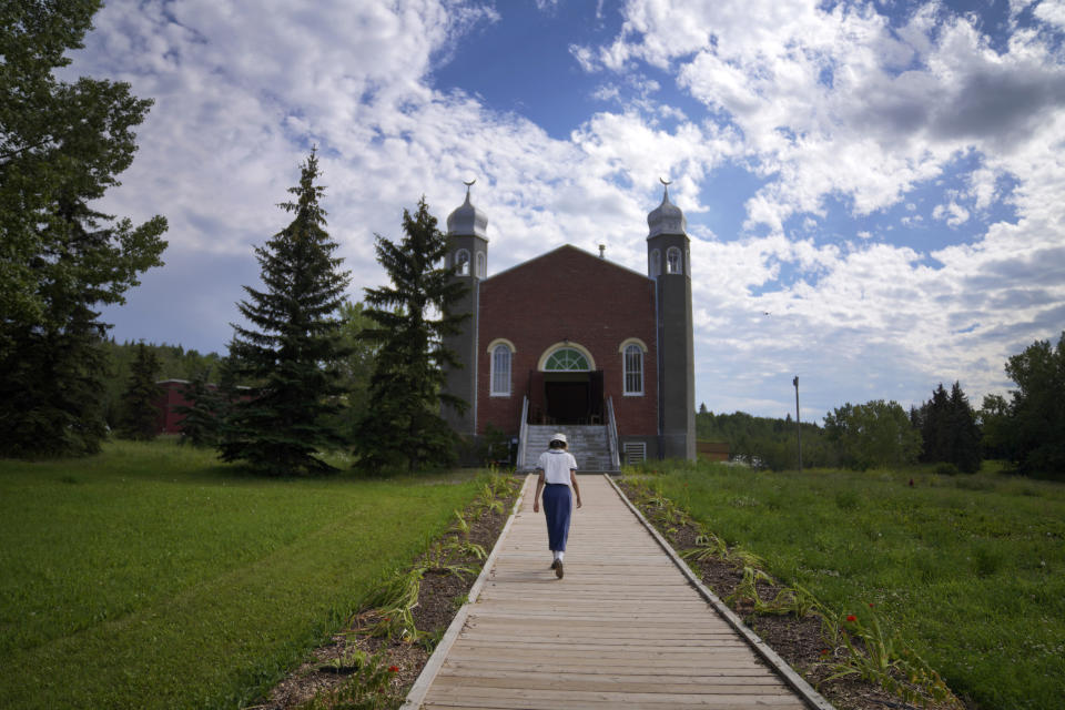 A woman walks down the pathway to the historic Al-Rashid Mosque, believed to be Canada's oldest, Saturday, July 16, 2022, in Edmonton, Alberta. The original red-brick structure now stands in the city's heritage park. (AP Photo/Jessie Wardarski)