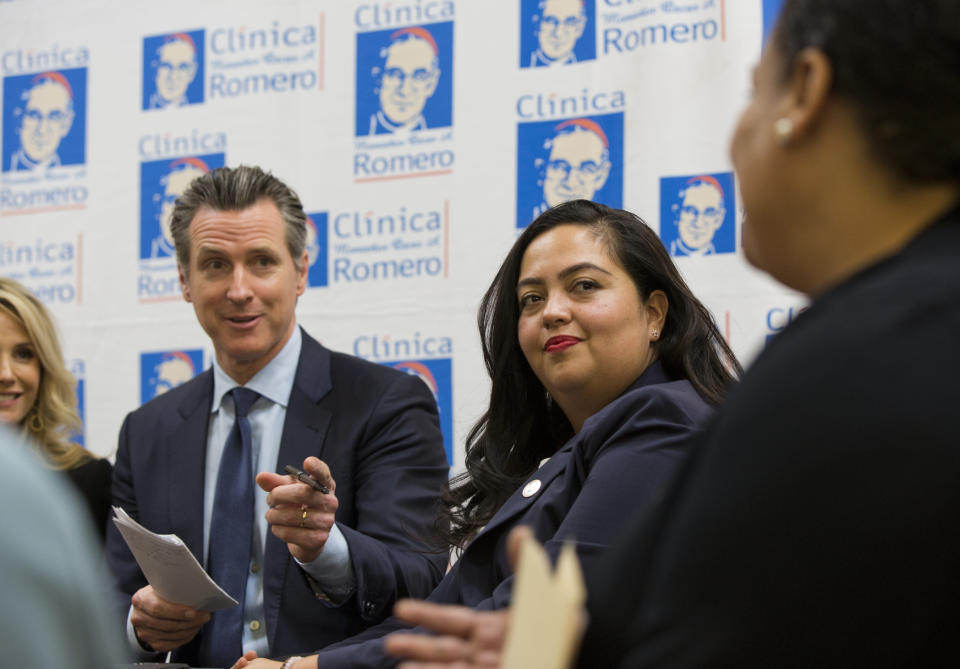 California Gov. Gavin Newsom, left, and Assemblymember Wendy Carrillo, right, representing the 51st California Assembly District listens during a roundtable discussion with Central American community leaders at the Clinica Monsenor Oscar Romero in Los Angeles Thursday, March 28, 2019. Newsom said Thursday he will travel to El Salvador in April to discuss the poverty and violence that's causing waves of migrants to seek asylum in the United States. (AP Photo/Damian Dovarganes)