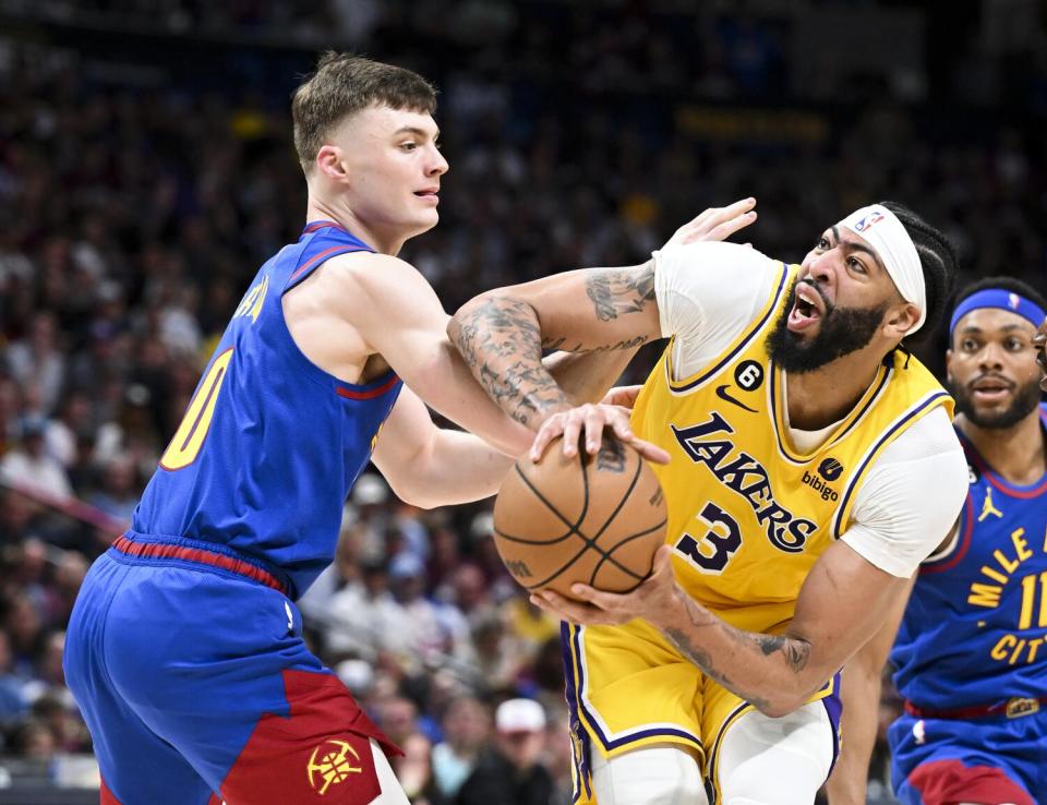 Lakers star Anthony Davis drives against Denver Nuggets guard Christian Braun.