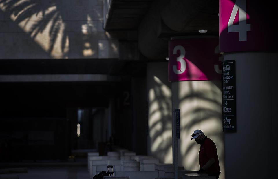 A traveler is silhouetted by the afternoon sun and shadows at John Wayne Airport.