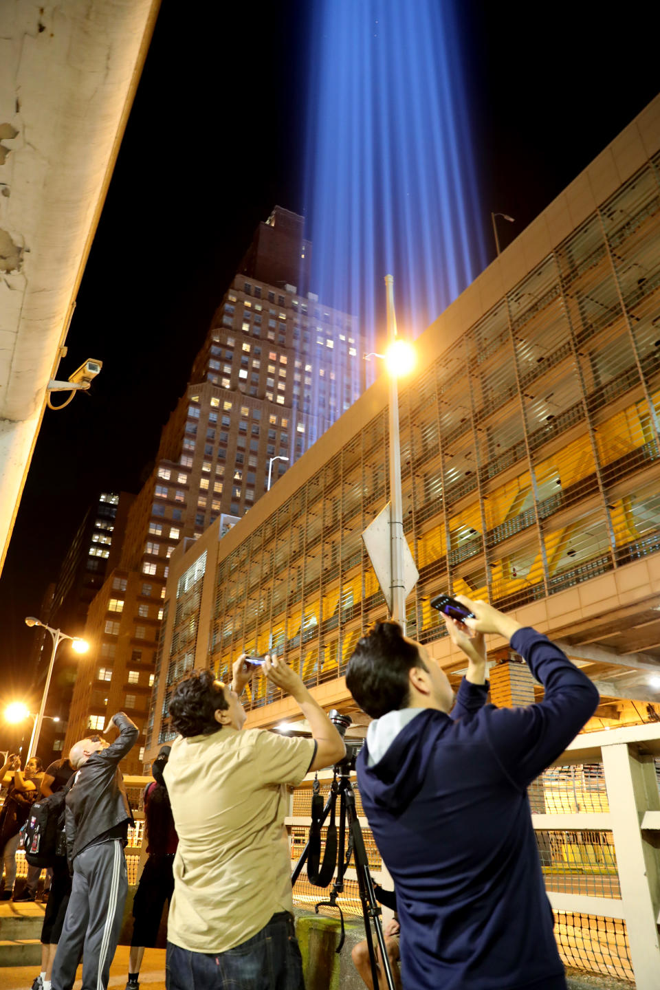 <p>People on the street take photos with their mobile device from the rooftop of where the beams of lights are projected on Sept. 11, 2017. (Gordon Donovan/Yahoo News) </p>