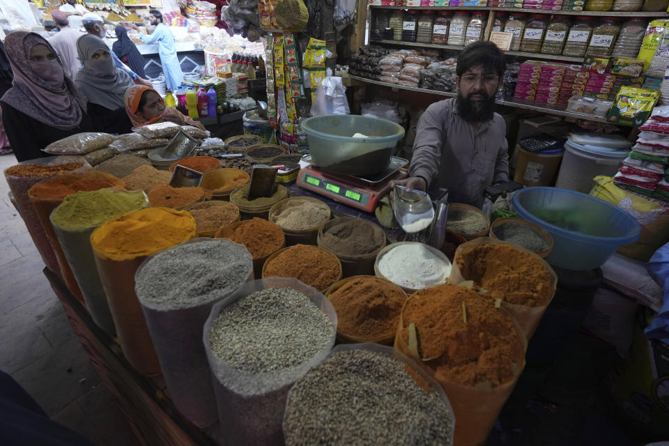 Women buy spices from a shop in a market, in Karachi, Pakistan, Tuesday, Feb. 14, 2023. Cash-strapped Pakistan nearly doubled natural gas taxes Tuesday in an effort to comply with a long-stalled financial bailout, raising concerns about the hardship that could be passed on to consumers in the impoverished south Asian country. Pakistan's move came as the country struggles with instability stemming from an economic crisis. (AP Photo/Fareed Khan)