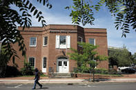 In this Monday, Aug. 5, 2019 photo a passer-by walks near an entrance to the Taunton Daily Gazette newspaper's offices, in Taunton, Mass. The newspaper is published by GateHouse Media New England, a division of GateHouse Media Inc. On Monday, GateHouse Media, a chain backed by an investment firm, announced that it is buying USA Today owner Gannett Co. (AP Photo/Steven Senne)