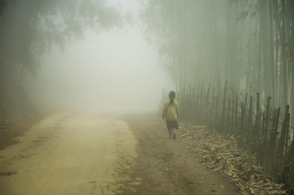 a woman is walking alone on a dirt road