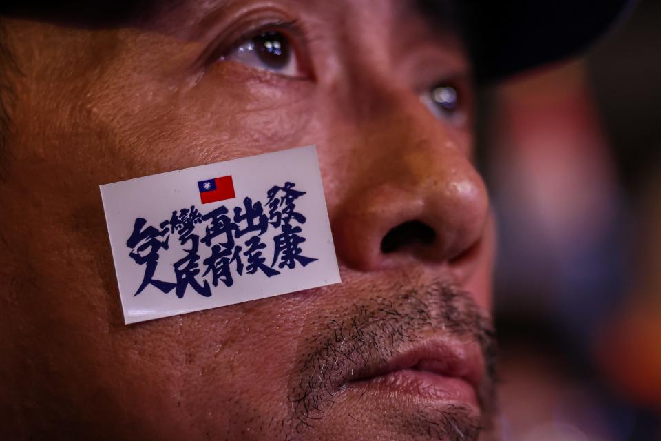 A supporter of the Kuomintang (KMT) wears a campaign slogan badge on his face during a rally on the eve of the general election on January 12, 2024, in Taipei, Taiwan.