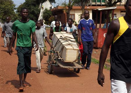 Men walk as they push a trolley loaded with a coffin in Bangui December 9, 2013. REUTERS/Emmanuel Braun