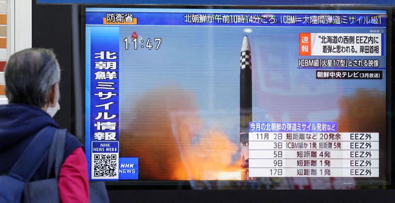 FILE PHOTO: A passerby looks at a television screen in Tokyo showing a news report about North Korea firing a ballistic missile