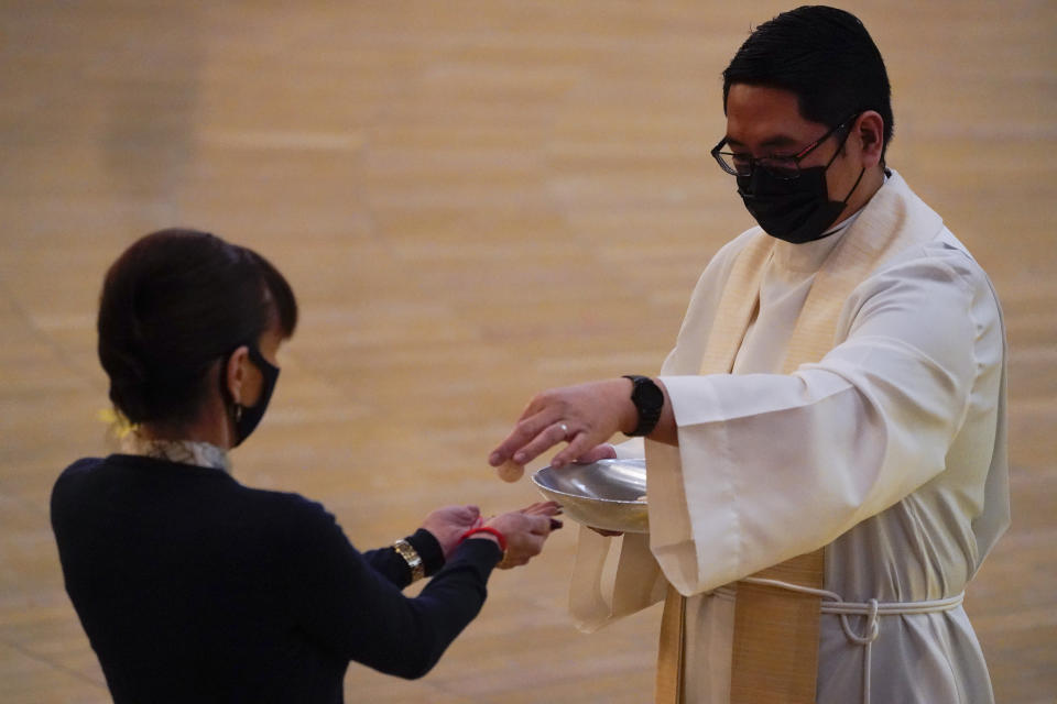 A woman receives communion during a Christmas Eve Mass inside the Cathedral of Our Lady of the Angels Thursday, Dec 24, 2020, in Los Angeles. California became the first state to record 2 million confirmed coronavirus cases, reaching the milestone on Christmas Eve as nearly the entire state was under a strict stay-at-home order and hospitals were flooded with the largest crush of cases since the pandemic began. (AP Photo/Ashley Landis)