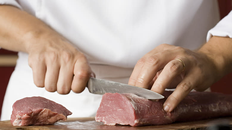 chef slicing raw tenderloin