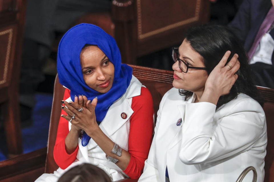 In this Feb. 5, 2019, photo, Rep. Ilhan Omar, D-Minn., left, joined at right by Rep. Rashida Tlaib, D-Mich., listens to President Donald Trump's State of the Union speech, at the Capitol in Washington. A tweet by Omar has sparked a bipartisan backlash, with some accusing her of being anti-Semitic. (AP Photo/J. Scott Applewhite)