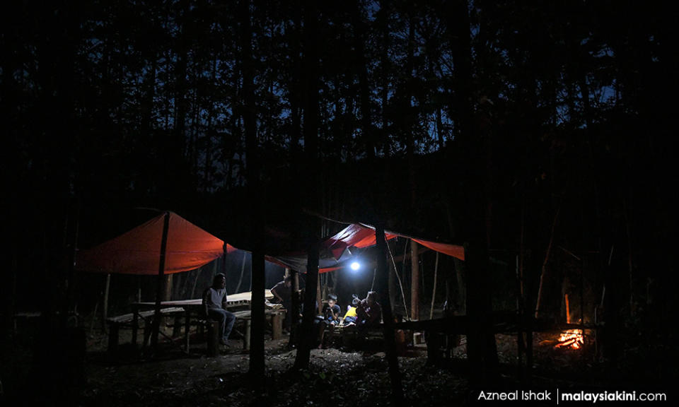 Night has fallen but parents continue to accompany their children as they attend online classes at the hut.