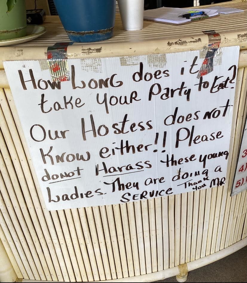 The sign reads "how long does it take your party to eat? Our hostess doesn't know either! Please do not harass these young ladies, they are doing a service"