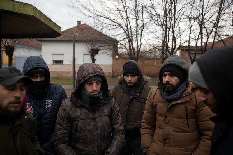 Migrants stand at a bus stop near the Hungary-Serbia border in Horgos