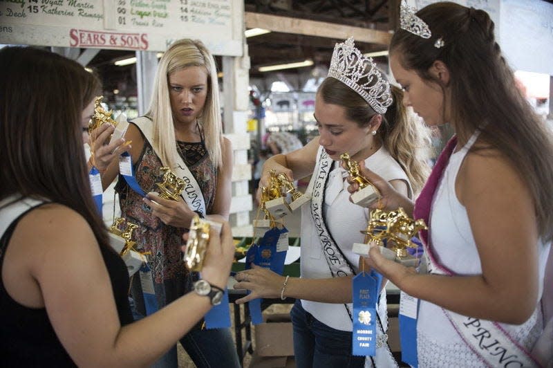 Monroe County Fair Queen 2017 Bethany Stanger organizes trophies and ribbons for her court to distribute to winners in a dairy show. This year's contest will be the fair's 72nd.