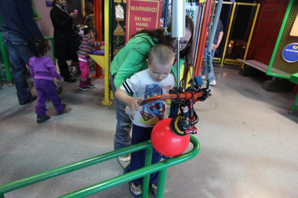 A young visitor gets help from his mom with the vacuum lifter at the Michigan Science Center.