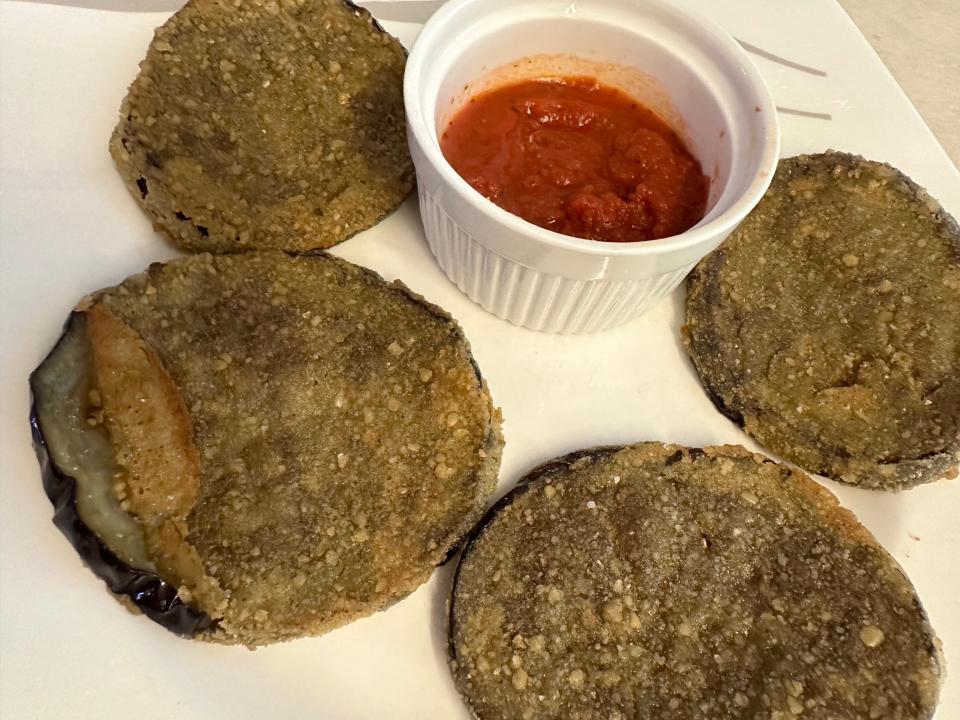 eggplant cutlets with bowl of sauce for dipping on white plate