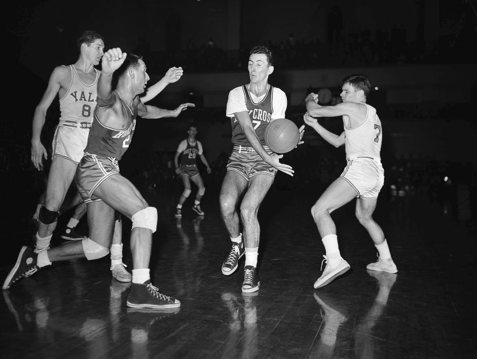 FILE - Bob Cousy, Holy Cross forward, second from right, intercepts a pass intended for Tony Lavelli, (8) of Yale, left, in first period of an NCAA college basketball game Feb. 19, 1949, in New Haven, Conn. Rob McMullen of Holy Cross, left, comes in on the play. Art Fizgerald, (7) of Yale is at right. (AP Photo/File)