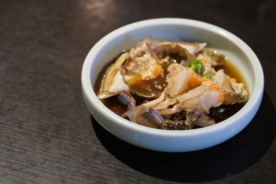 raw crab in small white bowl in soy sauce