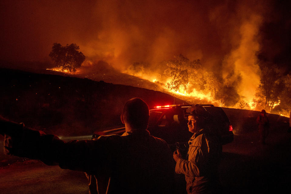 Firefighters confer while battling the Kincade Fire near Geyserville, Calif., on Thursday, Oct. 24, 2019. Portions of Northern California remain in the dark after Pacific Gas & Electric cut power to prevent wildfires from sparking during dry and windy conditions. (Photo: Noah Berger/AP)