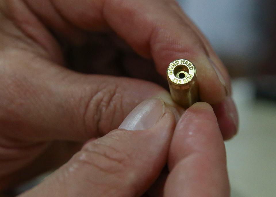 Barry Skolnick, owner of Grind Hard Ammo facility holds a shell casing on Thursday, Feb. 23, 2023.