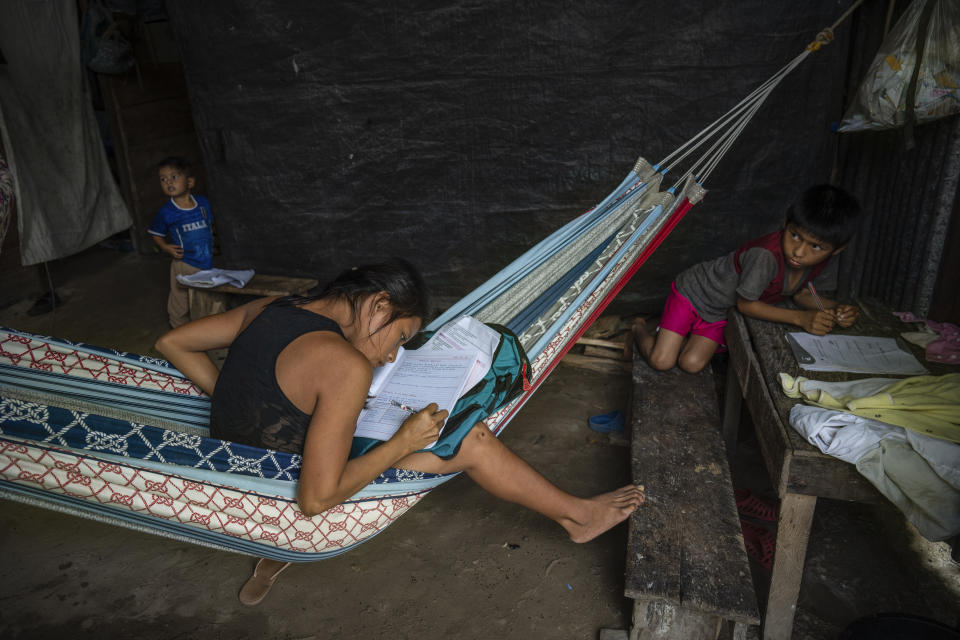 Murui youth Emerita does her Religious Studies homework while sitting in a hammock at her home in Nuevo Arenal, Peru, Tuesday, May 28, 2024. A federal highway project in an untouched area of the Peruvian Amazon is facing mounting opposition from Indigenous tribes, including the Murui. (AP Photo/Rodrigo Abd)