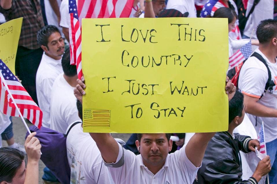 Man holds sign saying "I love this country" along with hundreds of thousands of immigrants participating in march for Immigrants and Mexicans protesting against Illegal Immigration reform by U.S. Congress, Los Angeles, CA, May 1, 2006