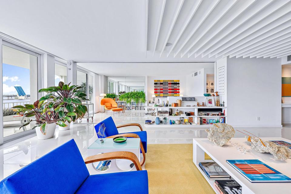 A half-height partition with a shelf unit separates the living room from the main bedroom, with the orange chair, in the rear.