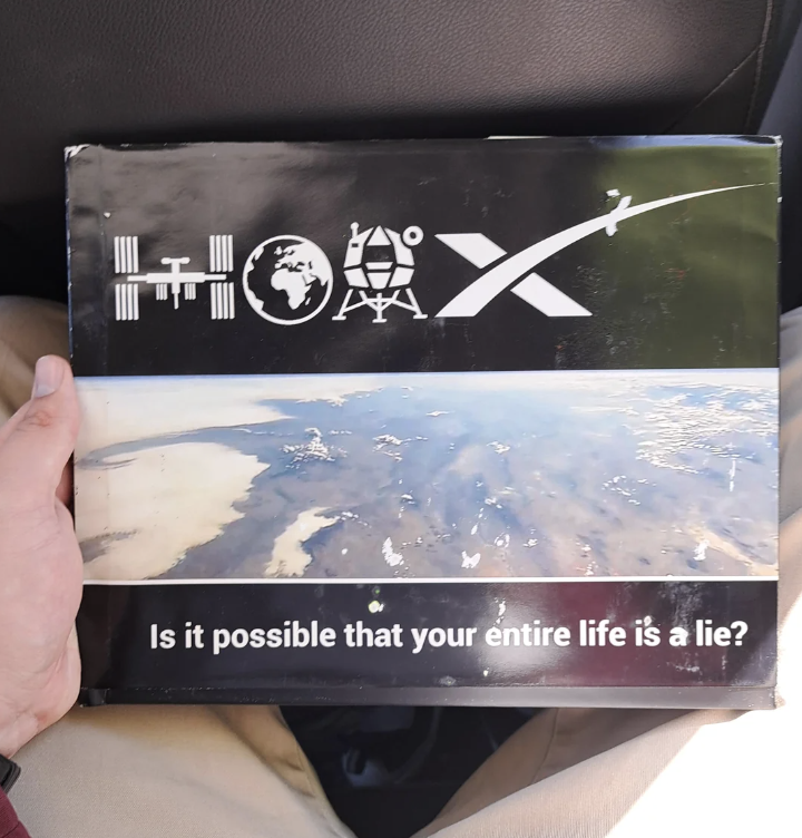 Box with various symbols and text "Is it possible that your entire life is a lie?" held in a person's lap