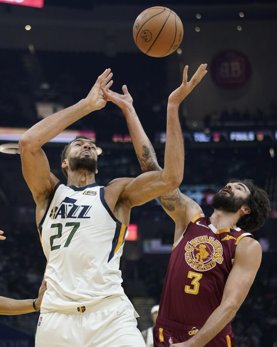 Utah Jazz's Rudy Gobert (27) and Cleveland Cavaliers' Ricky Rubio (3) battle for a loose ball in the first half of an NBA basketball game, Sunday, Dec. 5, 2021, in Cleveland. (AP Photo/Tony Dejak)