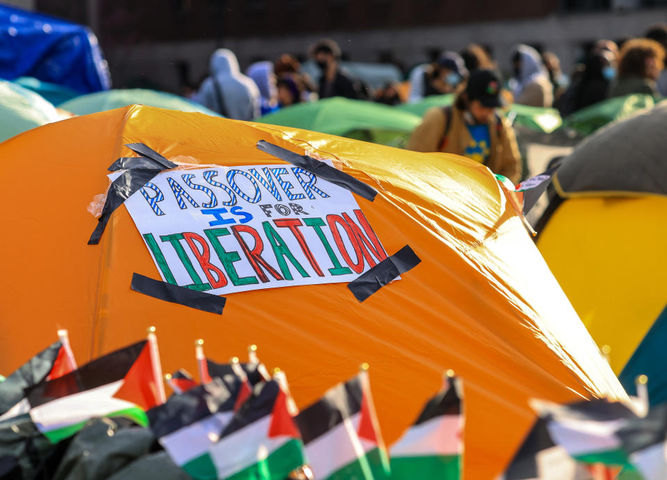 Sign on tent reads "Passion for Liberation" at a crowded outdoor event with flags