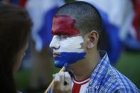 A girl paints a youth's face with the colors of the Paraguayan flag during a protest against the project to change the country's constitution, in Asuncion, Paraguay, Thursday, March 30, 2017. The country's upper house of Congress is split over a proposal to amend the constitution and allow for the re-election of former presidents. (AP Photo/Jorge Saenz)