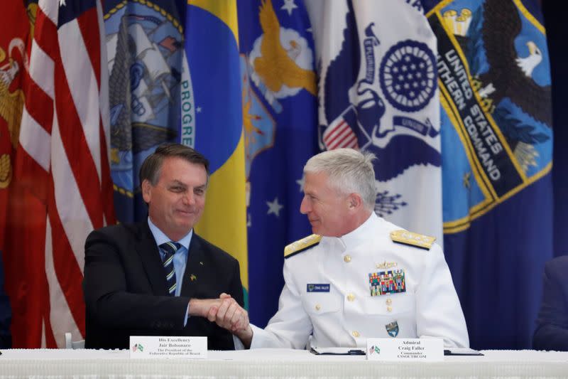 Brazilian President Jair Bolsonaro and Commander of the U.S. Southern Command Admiral Craig S. Faller shake hands during an agreement signing ceremony, in Miami