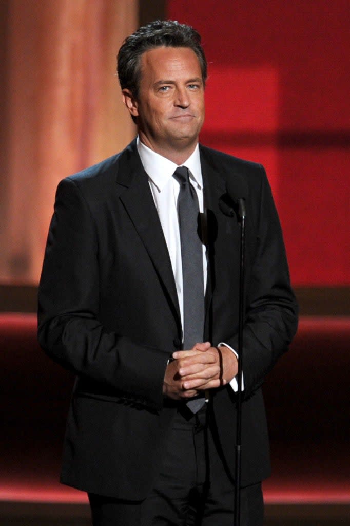 Matthew in a classic suit and tie standing on stage