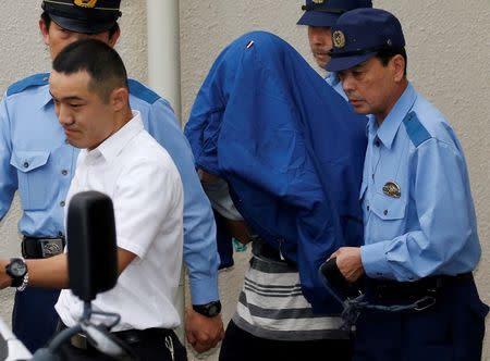 Satoshi Uematsu (C, with a jacket over his head), suspected of a deadly attack at a facility for the disabled, is escorted by police officers as he is taken from local jail to prosecutors, at Tsukui police station in Sagamihara, Kanagawa prefecture, Japan, July 27, 2016. REUTERS/Issei Kato - RTSJSQL