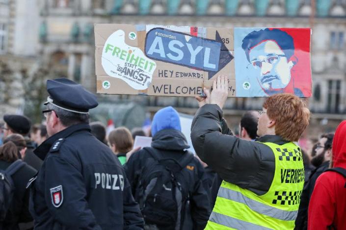 Protestors hold up placards featuring a picture of former NSA contractor Edward Snowden with the world "Asylum" during a march against the spying methods of the US in Hamburg, on December 28, 2013 (AFP Photo/Bodo Marks)