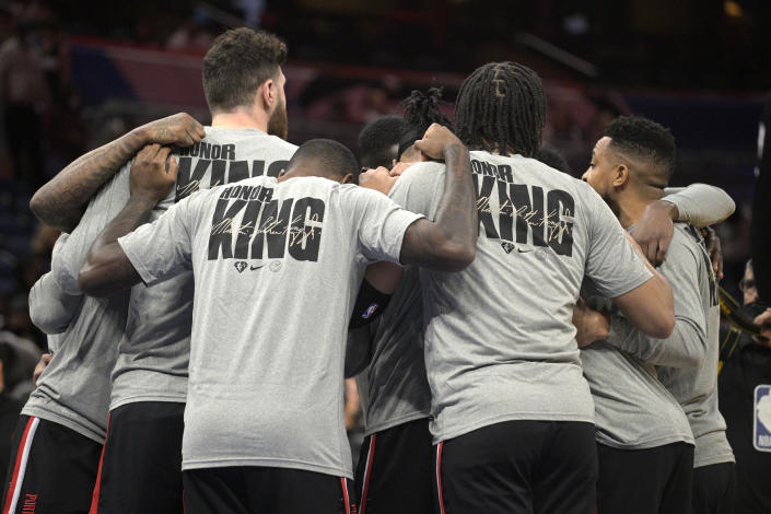 Portland Trail Blazers players huddle on the court while wearing T-shirts honoring Martin Luther King Jr. before an NBA basketball game against the Orlando Magic, Monday, Jan. 17, 2022, in Orlando, Fla. (AP Photo/Phelan M. Ebenhack)