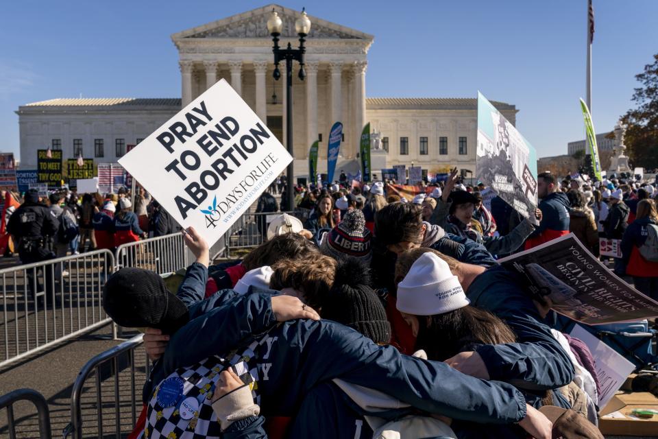 A group of anti-abortion protesters pray together in front of the U.S. Supreme Court, Wednesday, Dec. 1, 2021, in Washington, as the court hears arguments in a case from Mississippi, where a 2018 law would ban abortions after 15 weeks of pregnancy, well before viability.