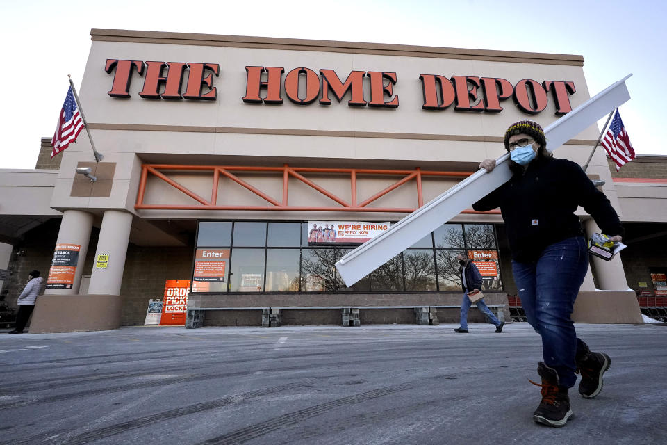 Passers-by walk near an entrance to a Home Depot home improvement store Sunday, Feb. 21, 2021, in Boston. The Home Depot’s fiscal fourth-quarter sales surged 25% as the home improvement chain continues to meet the demands of consumers stuck at home and a resilient housing market. (AP Photo/Steven Senne)