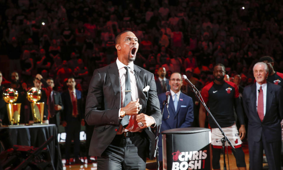 Former Miami Heat player Chris Bosh reacts at the team's retirement of his jersey at halftime of an NBA game between the Heat and the Orlando Magic, Tuesday, March 26, 2019, in Miami. Heat president Pat Riley is at right and left of Riley is Miami Heat guard Dwyane Wade. Bosh played 13 seasons, the first seven in Toronto and the last six in Miami. He averaged 19.2 points and 8.5 rebounds, was an All-Star 11 times and won two championships.(AP Photo/Joe Skipper)