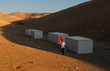 A man holds a Palestinian flag as he walks near shacks installed by activists to protest against the Israeli plan to demolish the Bedouin village of Khan al-Ahmar, in Khan al-Ahmar, occupied West Bank September 11, 2018. REUTERS/Mohamad Torokman