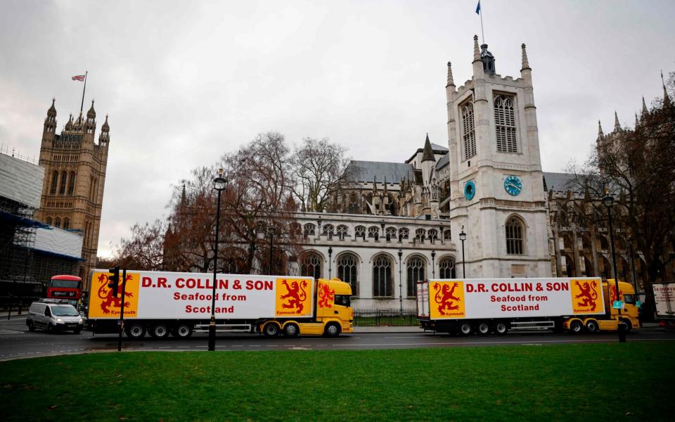 Lorries from Scottish seafood companies drive past the Houses of Parliament in a protest action - AFP