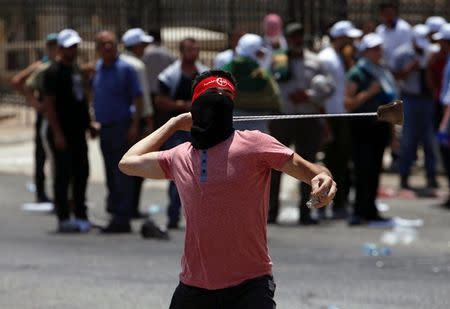A Palestinian protester uses a sling to hurl stones towards Israeli troops during clashes in the West Bank city of Bethlehem July 21, 2017. REUTERS/Mussa Qawasma